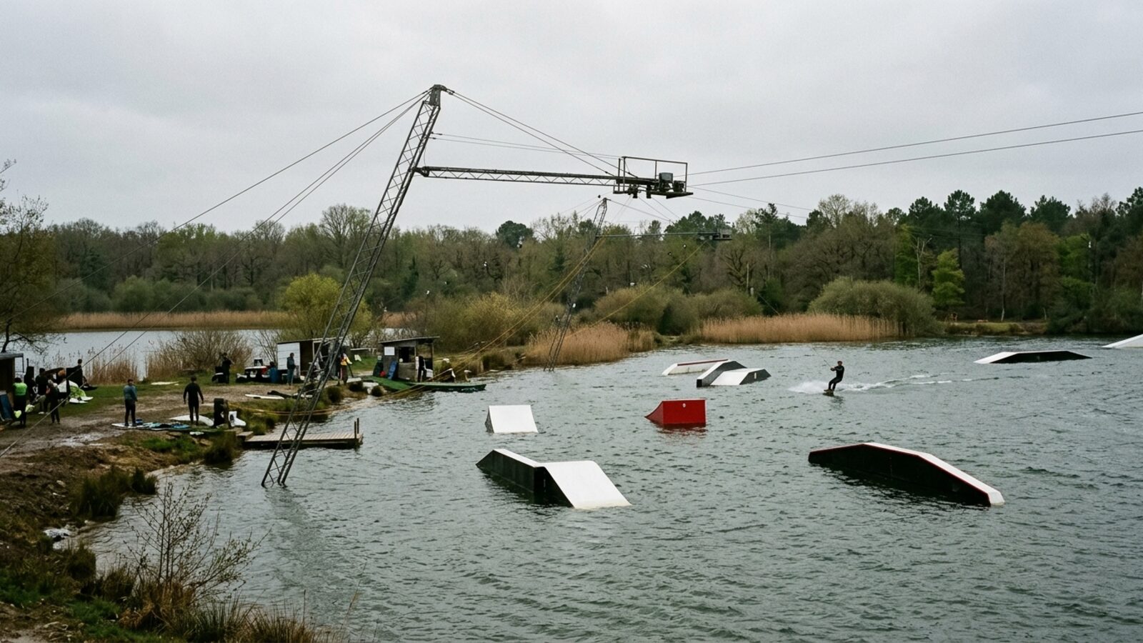 Illustration : teleski nautique sur un plan d eau, pylone et cable visibles, modules de glisse flottants et un rider tracte