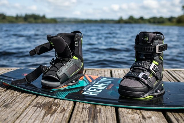 Paire de chausses de wakeboard avec sangles et boucles, fixées sur une planche posée sur un ponton